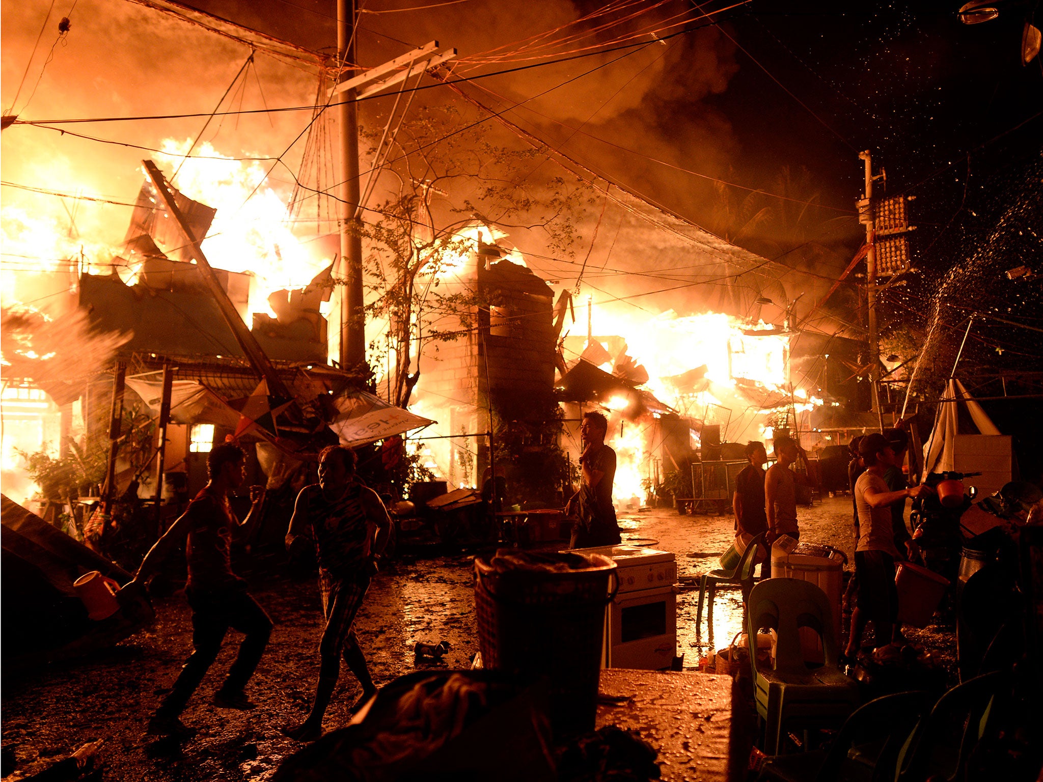 Local residents use water to try to fight a huge fire that razed a slum area in Manila on 1 January, 2016. Nearly 300 homes were destroyed in the early New Year's Day fire, according to local media reports