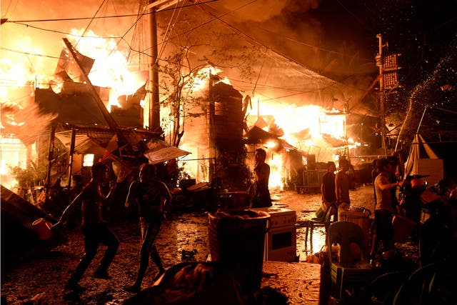 Local residents use water to try to fight a huge fire that razed a slum area in Manila on 1 January, 2016. Nearly 300 homes were destroyed in the early New Year's Day fire, according to local media reports