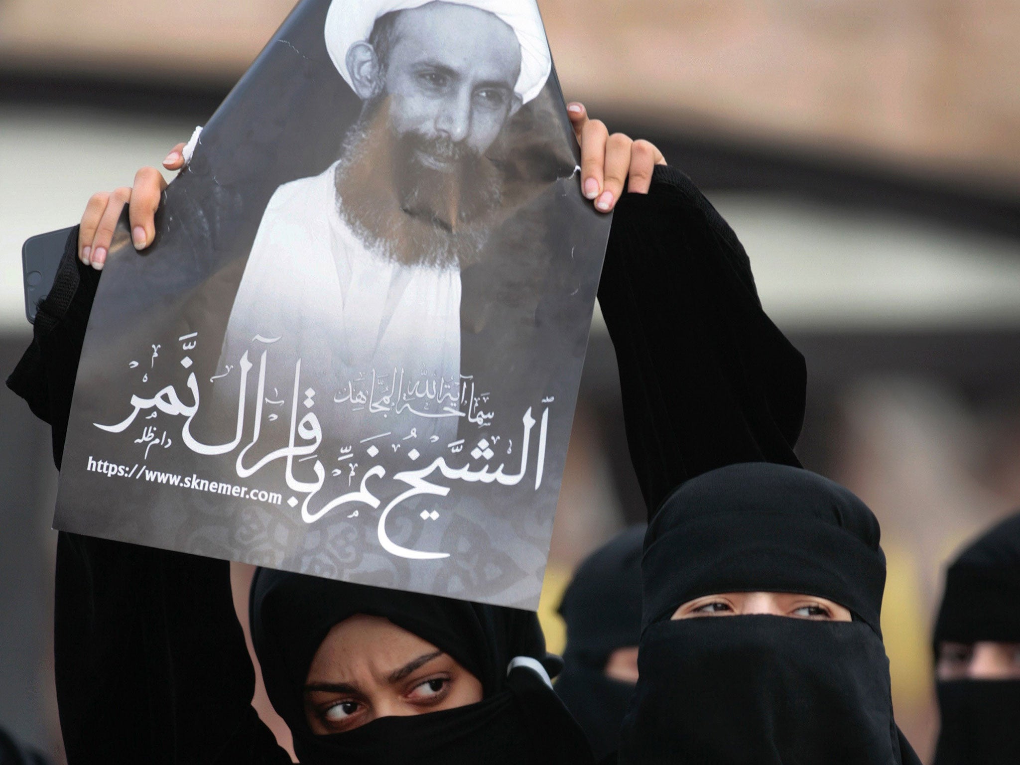 A protester holds a portrait of Sheik Nimr al-Nimr in Qatif