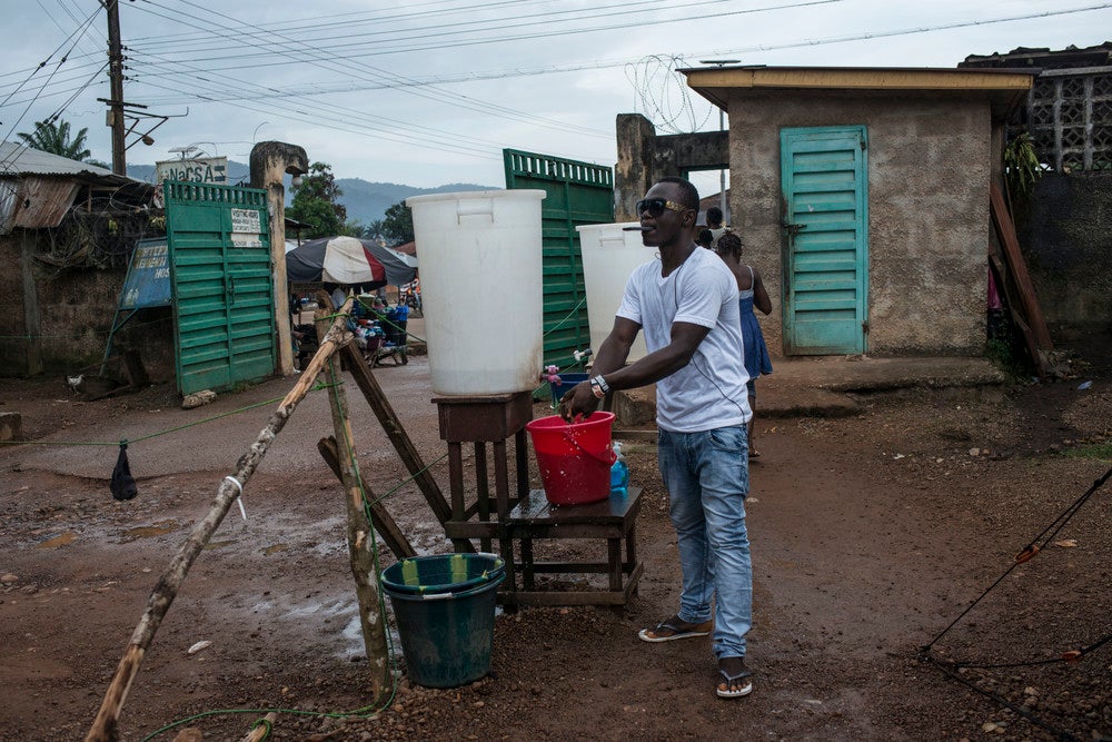 &#13;
A man washes his hands outside the Kenema Government Hospital in Kenema, Sierra Leone, November 2015. Sierra Leone was declared Ebola-free in November, however anyone entering the hospital is required to wash their hands and submit to a temperature check. Credit: WaterAid/Monique Jaques&#13;