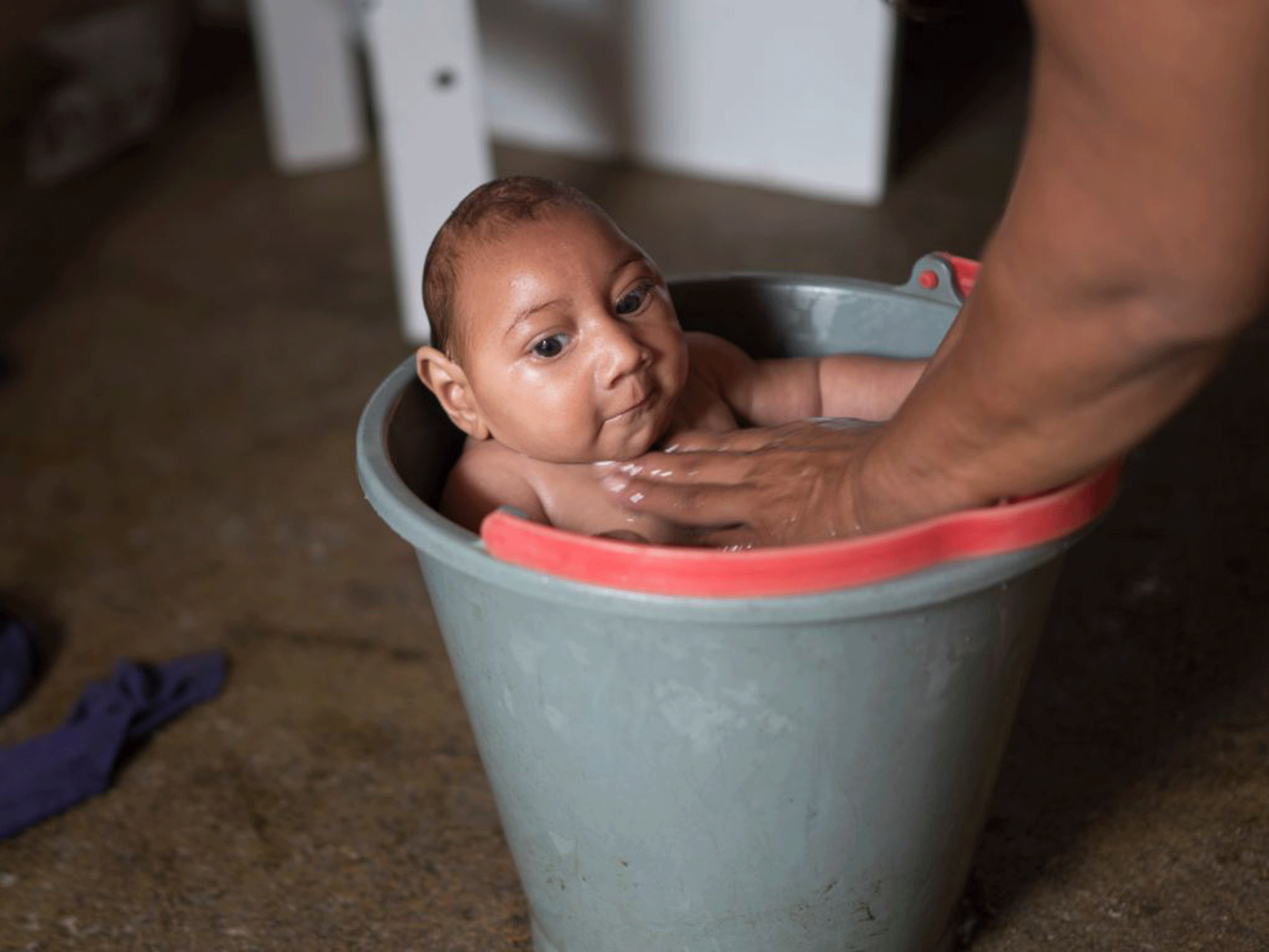 Solange Ferreira bathes her son Jose Wesley in a bucket of water, which she says he enjoys and helps calm him, at their home in Poco Fundo, Brazil.