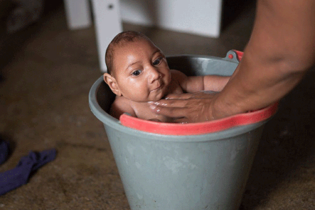 Solange Ferreira bathes her son Jose Wesley in a bucket of water, which she says he enjoys and helps calm him, at their home in Poco Fundo, Brazil.
