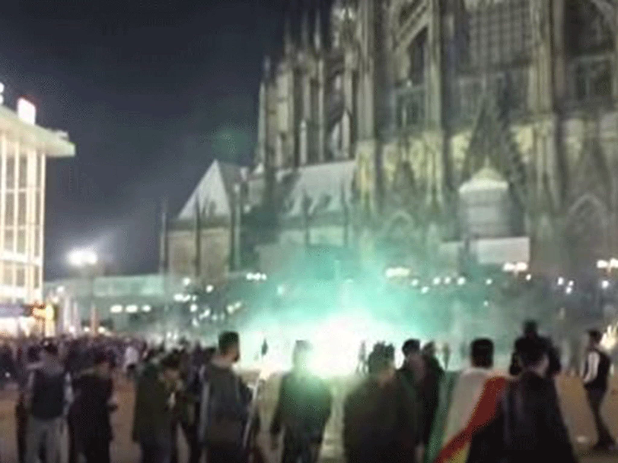 The crowd of men outside the cathedral and main train station in Cologne, with firecrackers being let off