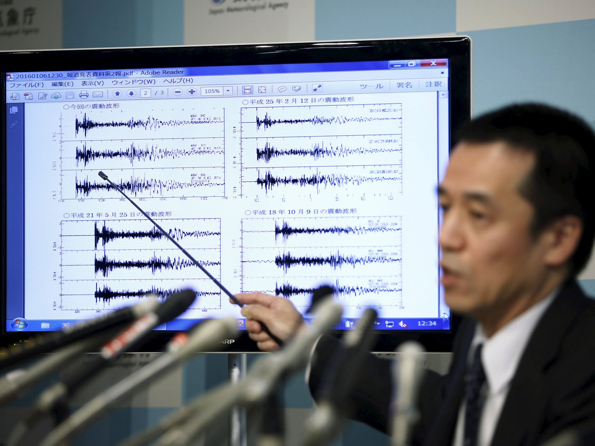 Japan Meteorological Agency's earthquake and tsunami observations division director Yohei Hasegawa points at a graph of ground motion waveform data observed in Japan