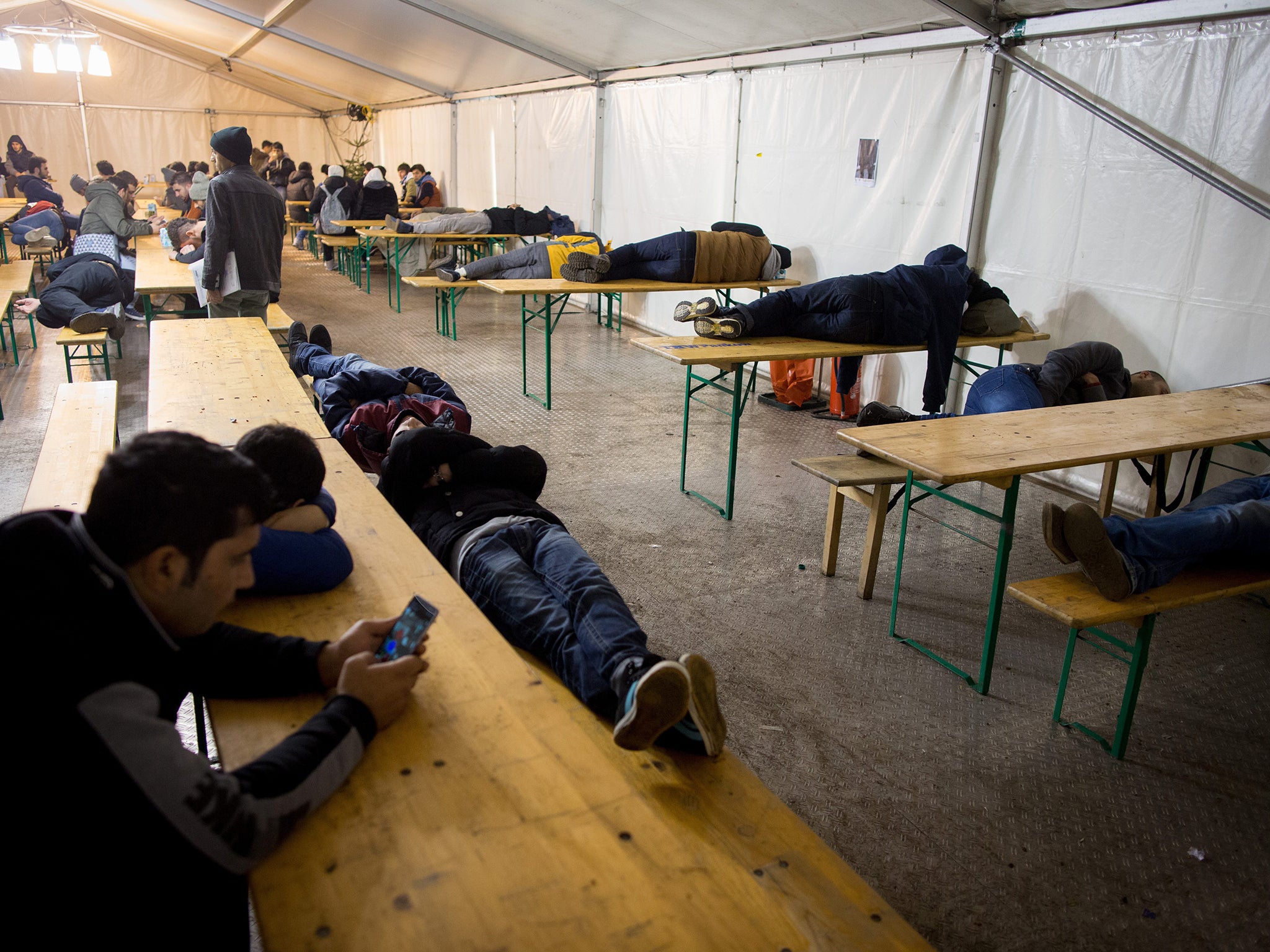 Asylum seekers sleep in a tent as they wait to register at the State Office of Health and Social Affairs registration centre in Berlin