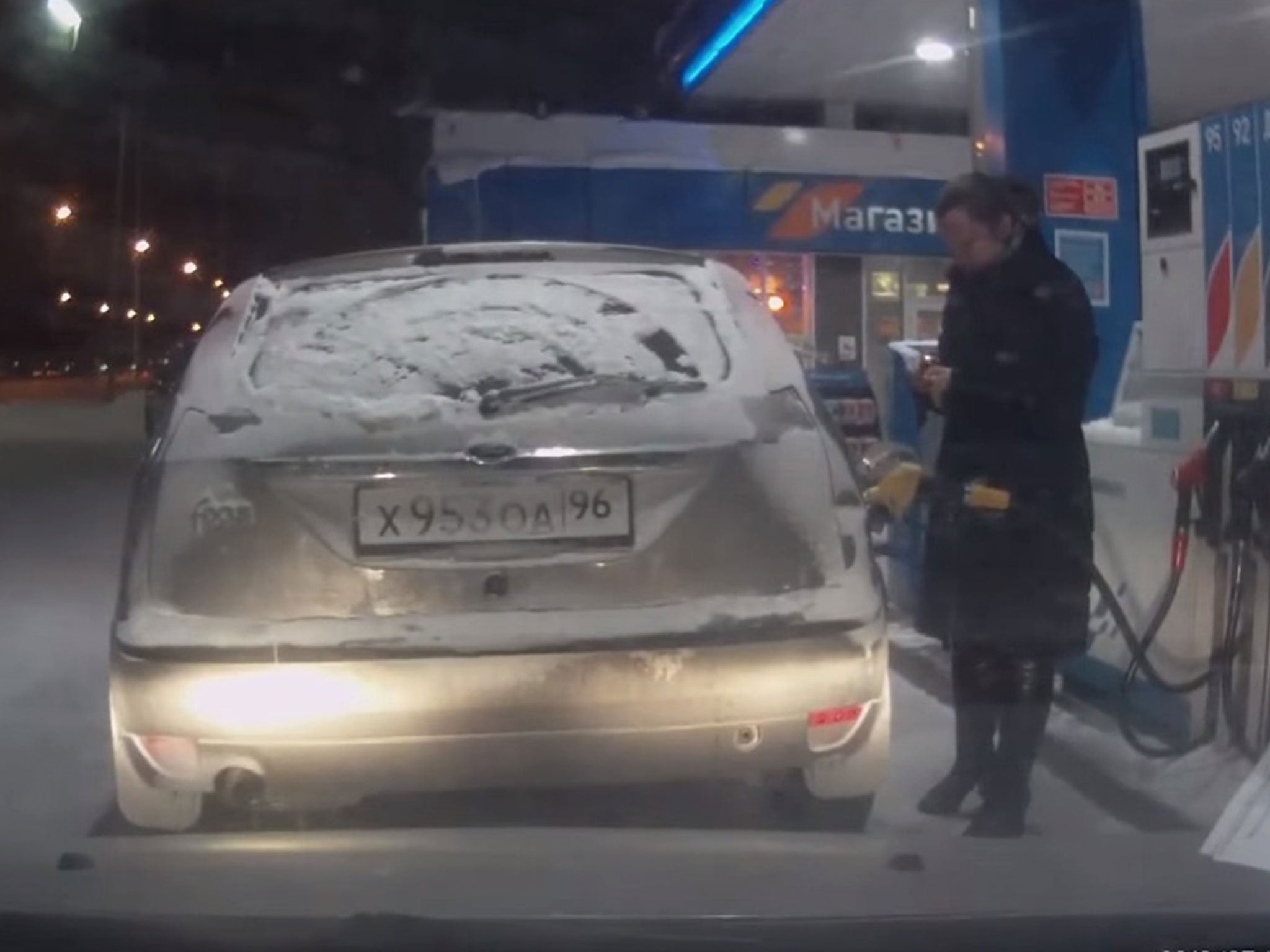 The woman is seen taking out a lighter and sparking up a flame, before peering into the car's petrol tank with it