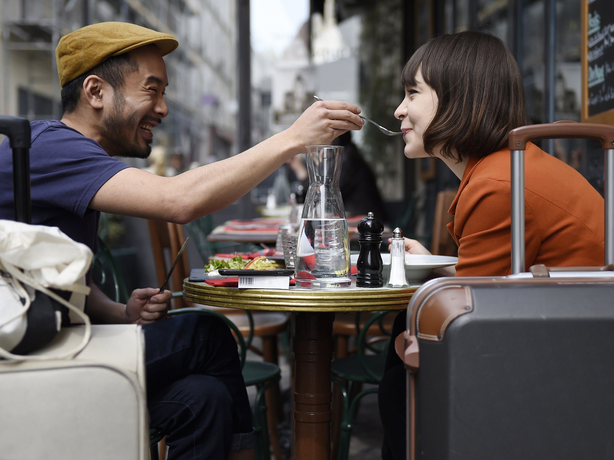 A man feeds his partner as they eat lunch at the terrace of a restaurant in Paris