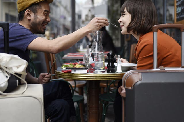 A man feeds his partner as they eat lunch at the terrace of a restaurant in Paris