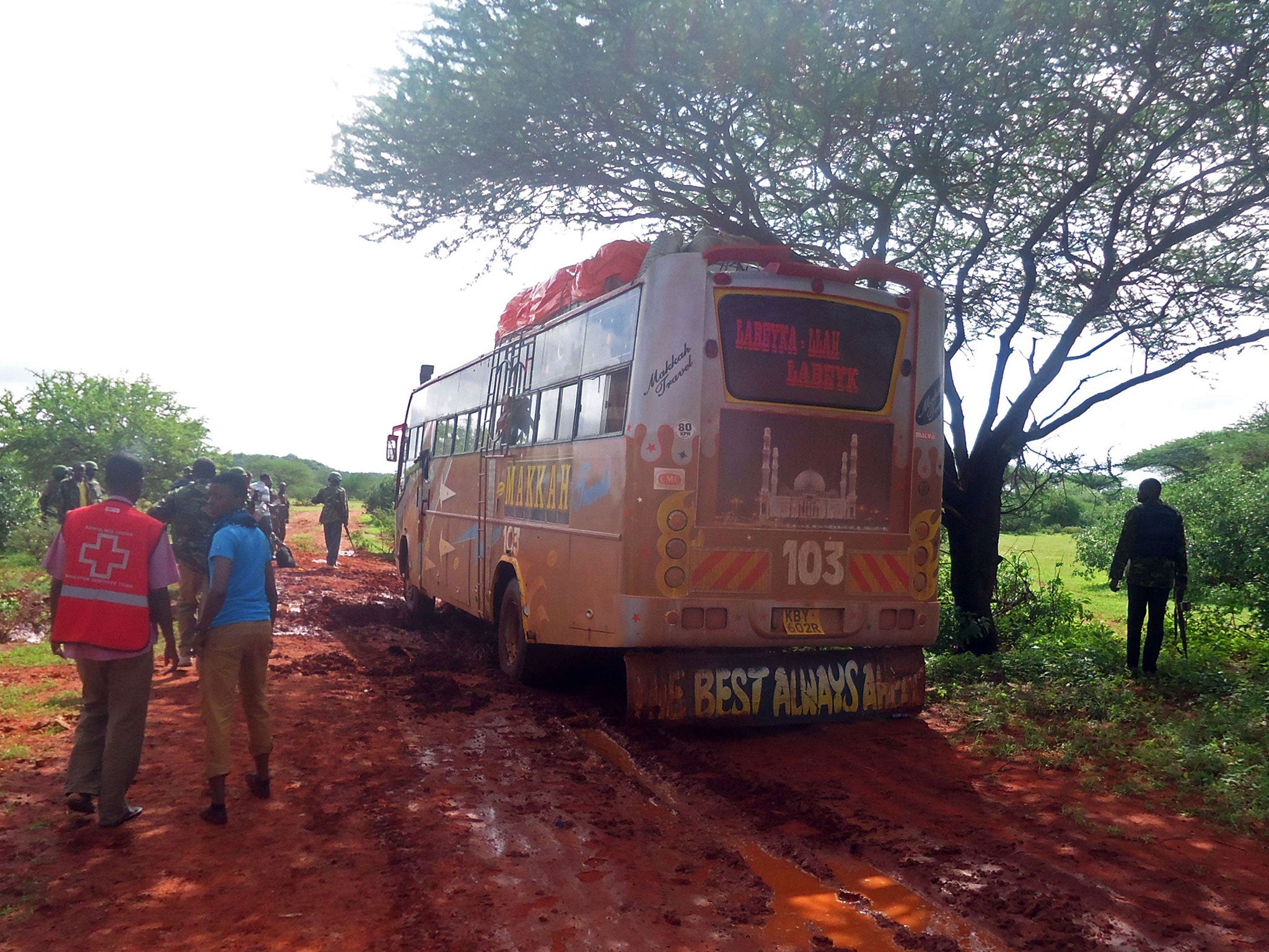 A medical worker and security forces walking near a bus which was attacked. 28 non-Muslim passengers were singled out from 60 and executed about 50 kilometres (31 miles) from the town of Mandera near Kenya's border with Somalia