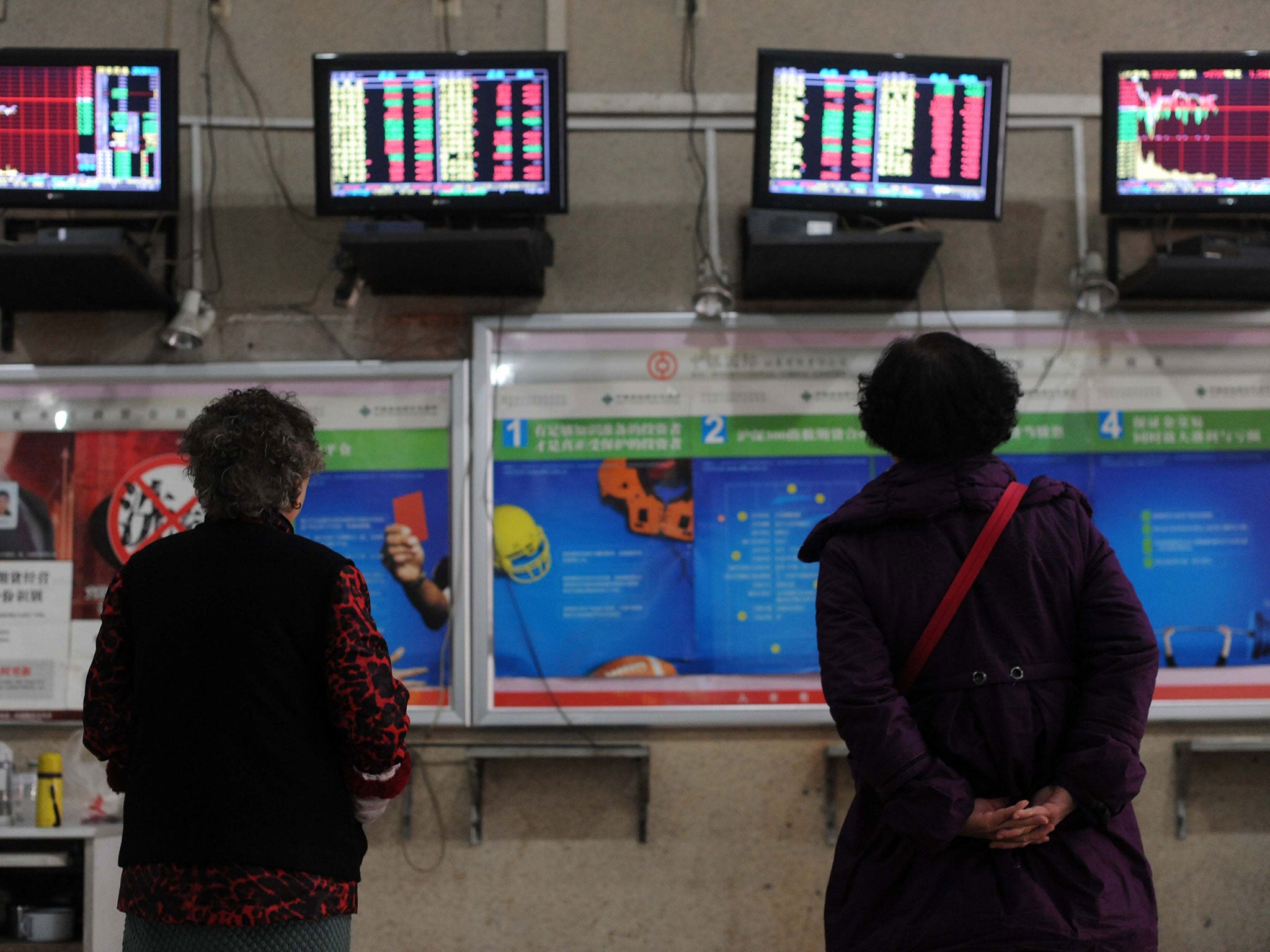 Two investors look at screens showing stock market movements in a stock firm in Wuhan, central China's Hubei province on January 8, 2016.