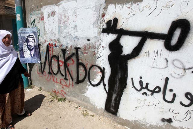 A Palestinian woman in the al-Aroub refugee camp, north of Hebron in the southern West Bank. The key in the graffiti is symbolic of the Palestinian refugee problem