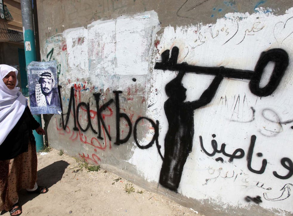A Palestinian woman in the al-Aroub refugee camp, north of Hebron in the southern West Bank. The key in the graffiti is symbolic of the Palestinian refugee problem
