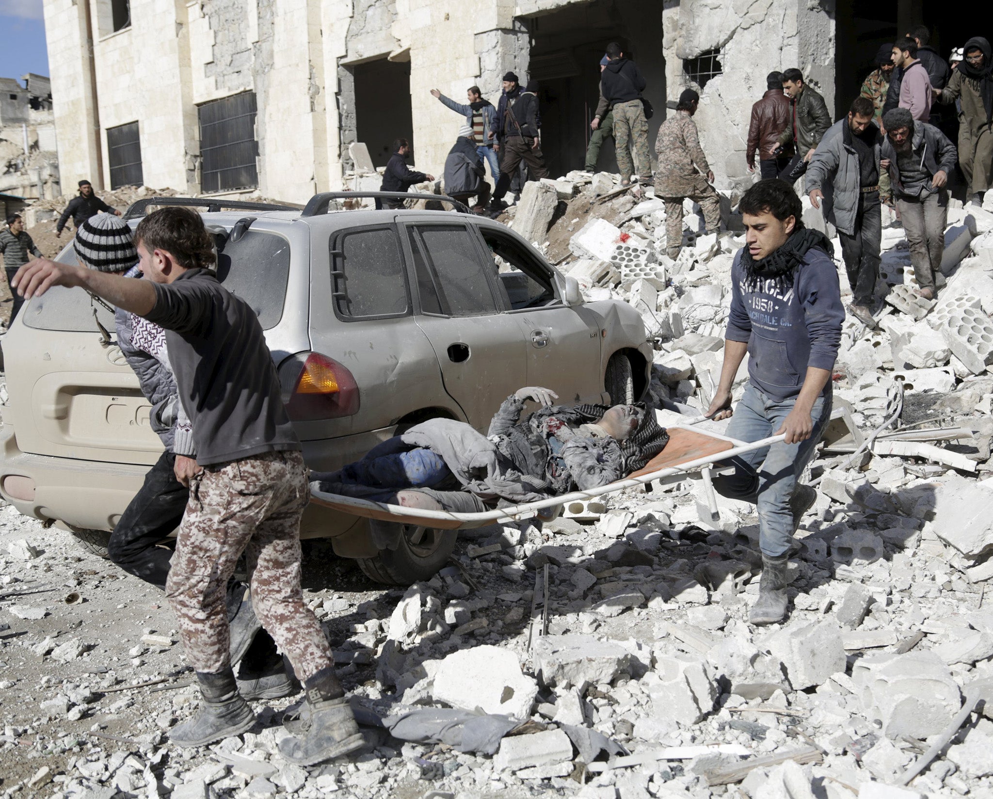 An injured woman is carried away from the wreckage of the prison in Maaret al-Numan
