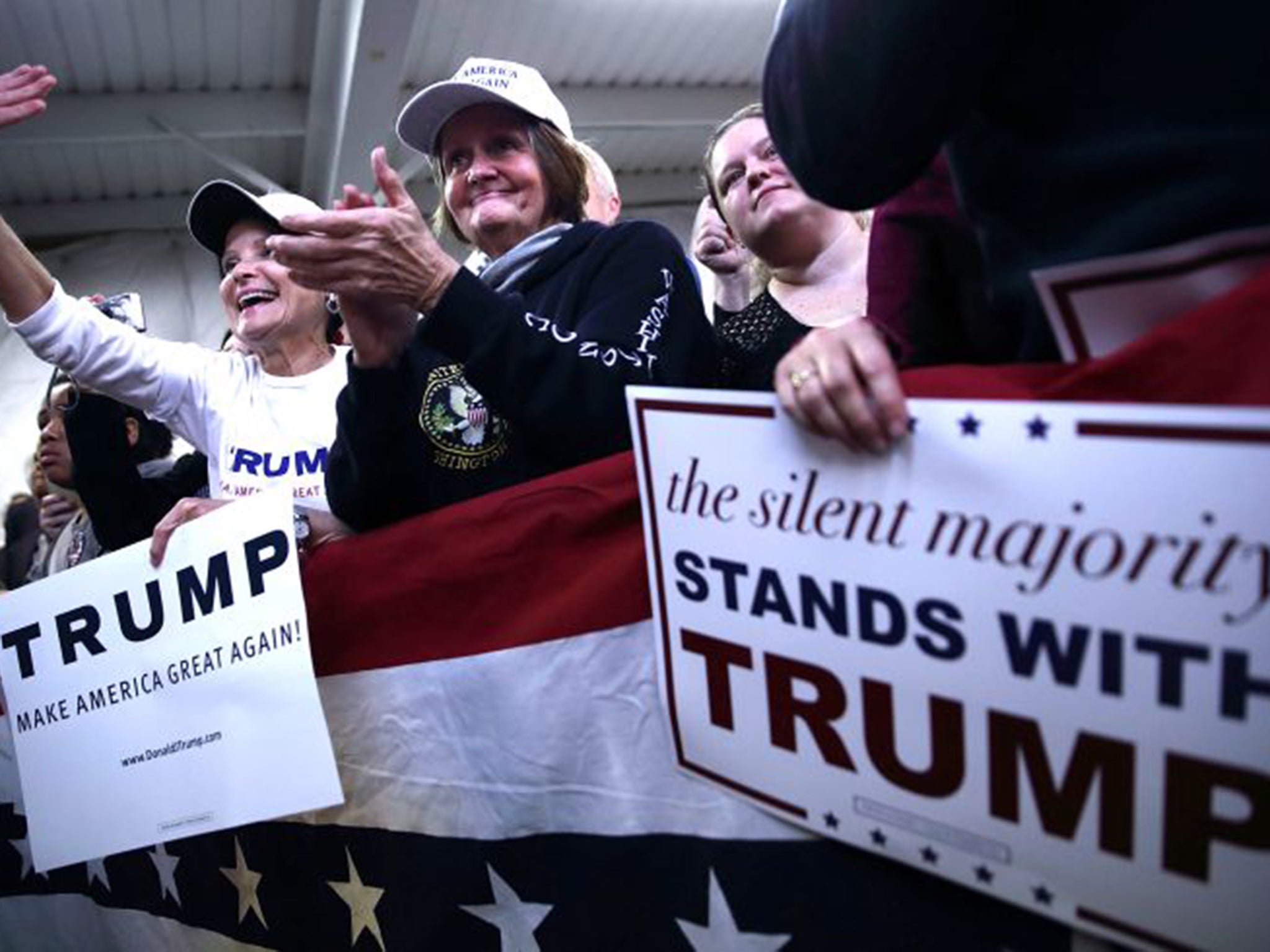 Supporters of Donald Trump listen on during a campaign rally in December