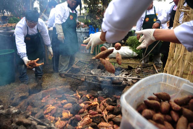 Cooks prepare a potato dish at a Lima food fair