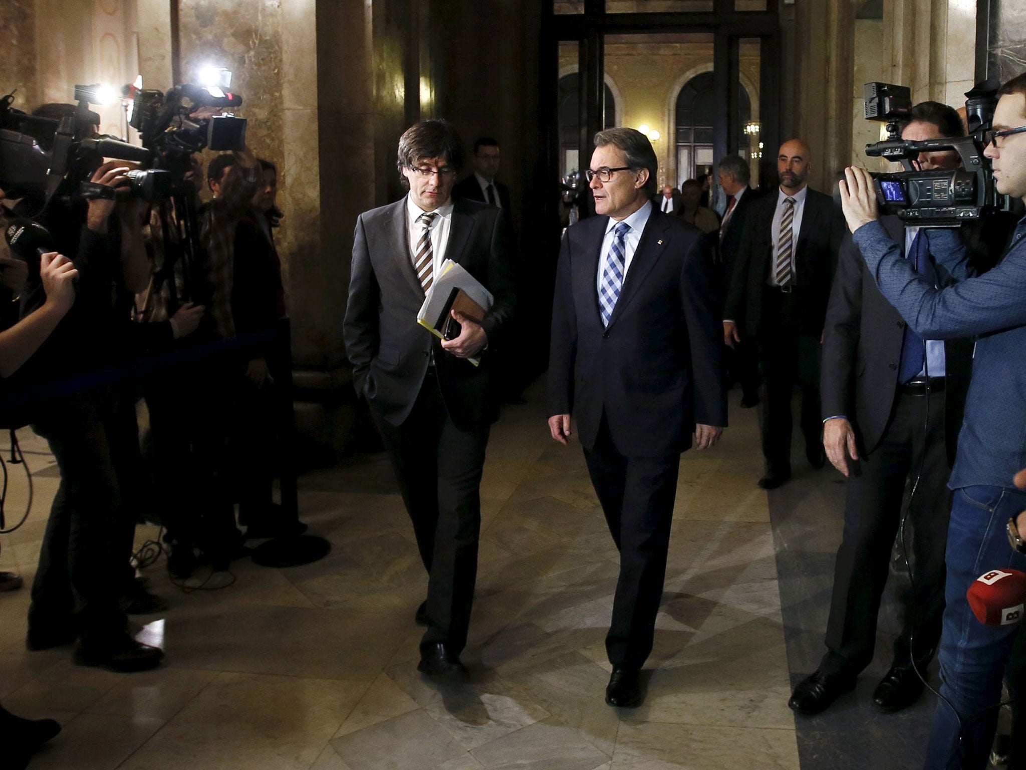 Incoming Catalan President Carles Puigdemont, left, and outgoing Catalan President Artur Mas speak in the corridors during a break of the investiture session at the Catalunya Parliament in Barcelona