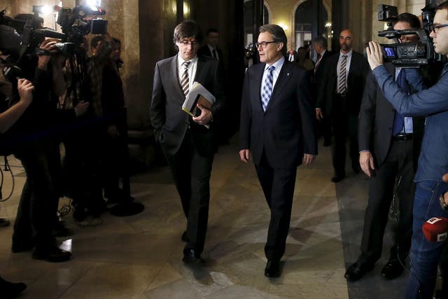 Incoming Catalan President Carles Puigdemont, left, and outgoing Catalan President Artur Mas speak in the corridors during a break of the investiture session at the Catalunya Parliament in Barcelona