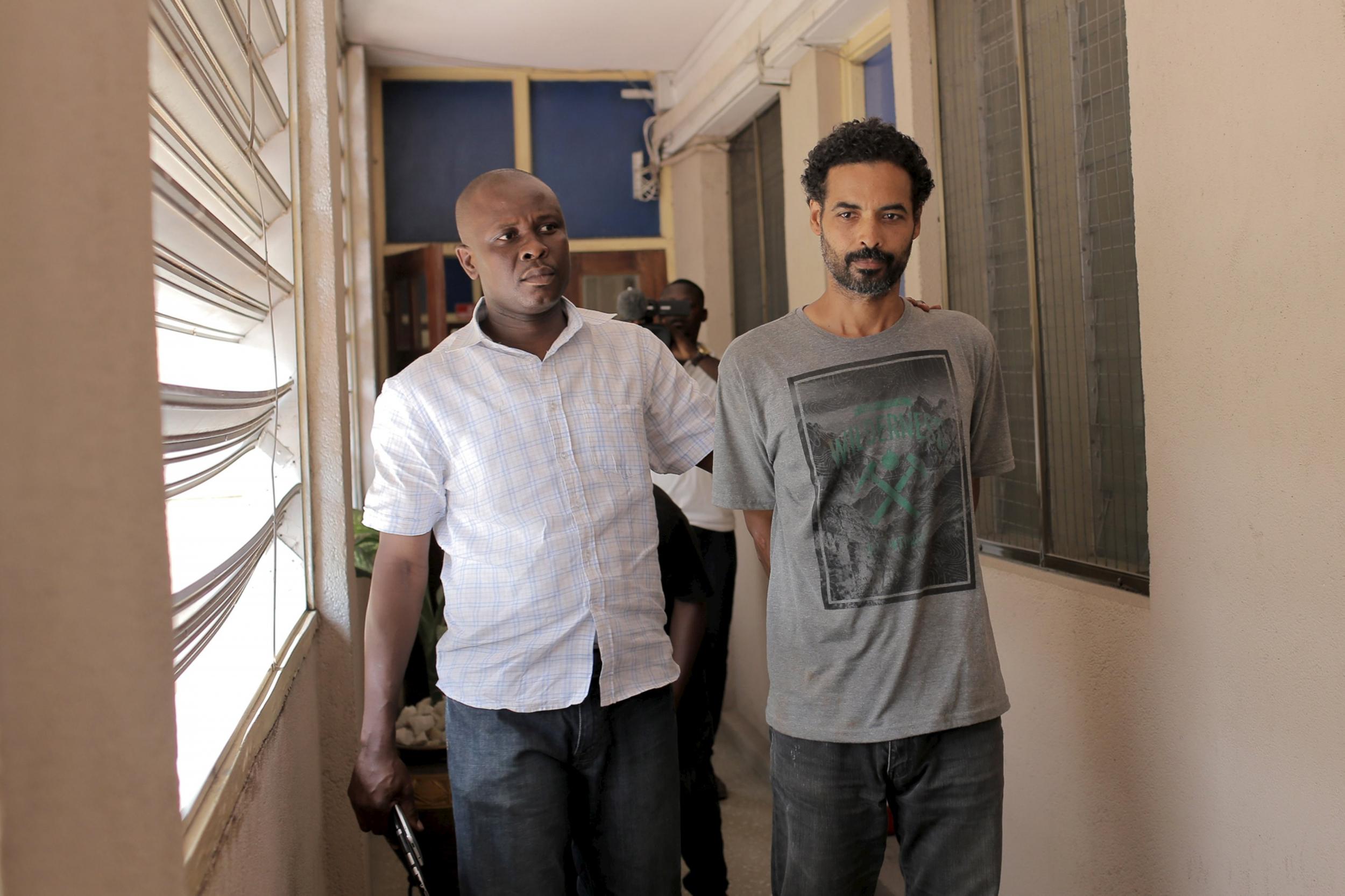 A Ghanaian police officer escorts Arthur Simpson-Kent inside the Criminal Investigation Department headquarters in Accra, Ghana