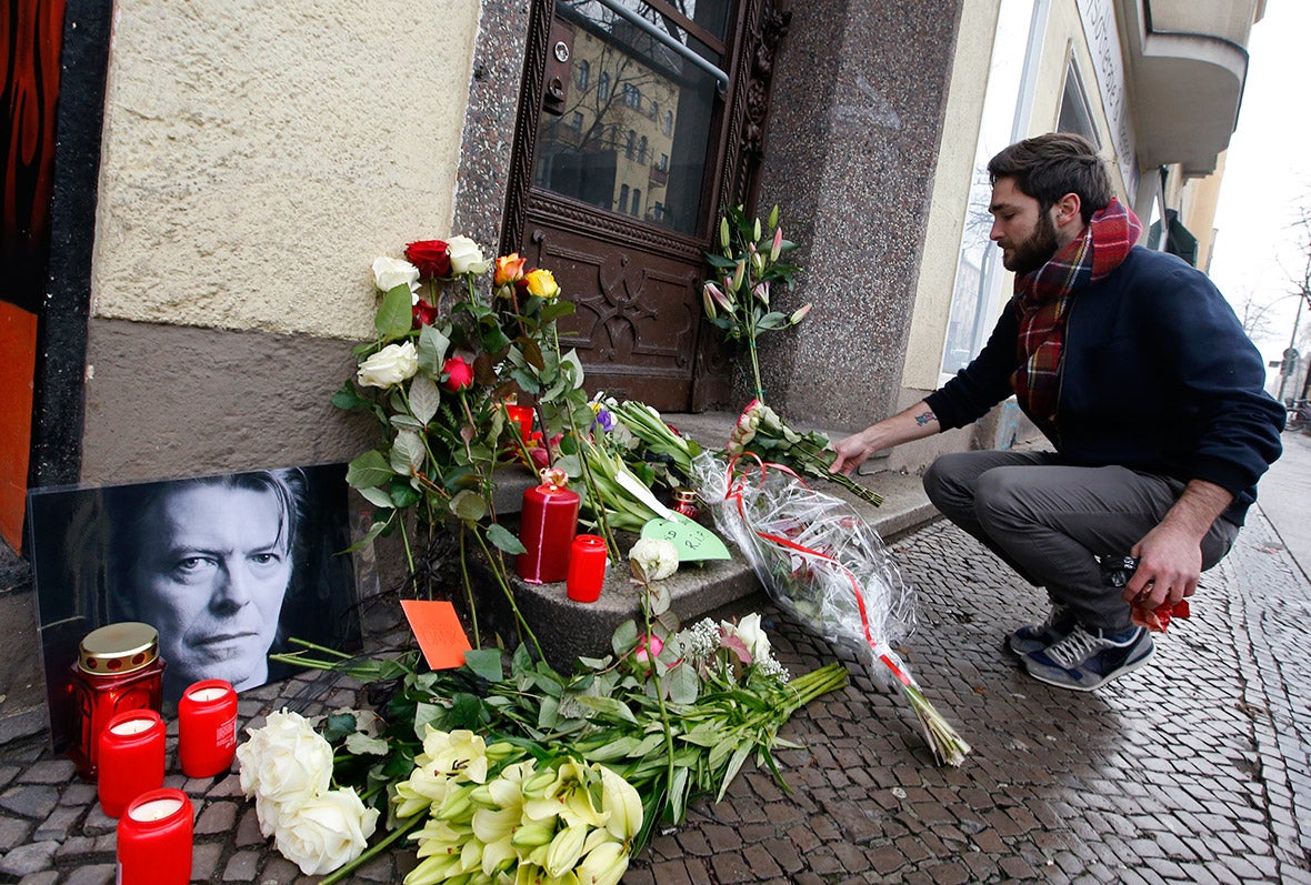 A fan places flowers outside Bowie's former home in Berlin.