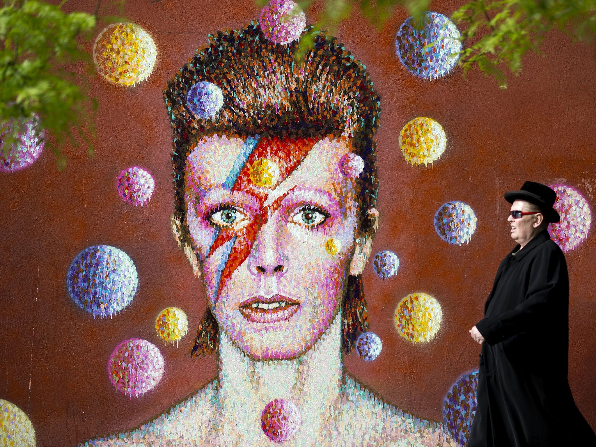 A man walks past a 3D wall portrait of British musician David Bowie, created by Australian street artist James Cochran, also known as Jimmy C, in Brixton, South London, on 19 June, 2013