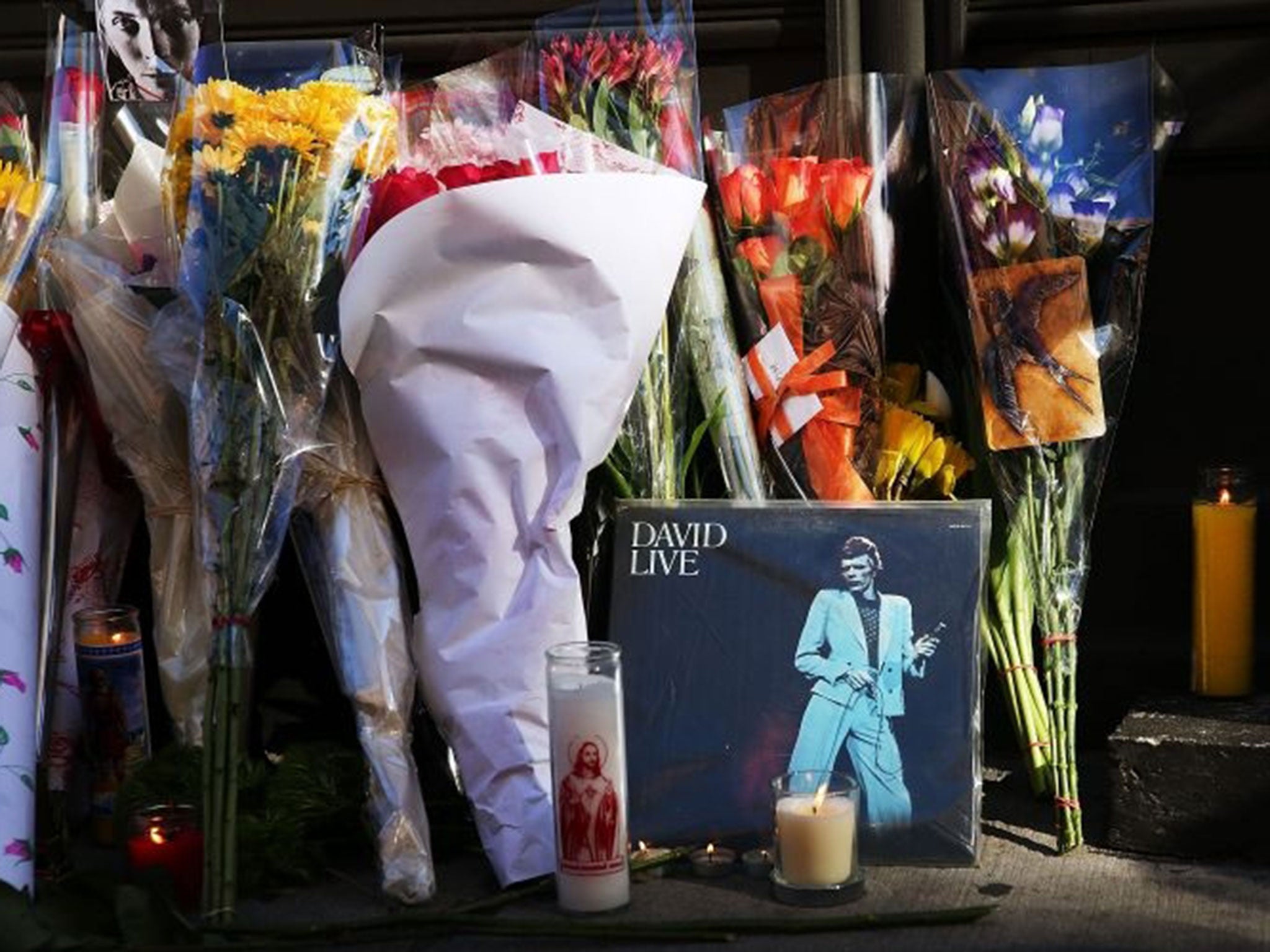Flowers, candles and pictures are some of the items deposited at a memorial outside of the late musician and performer David Bowie's apartment that he shared with his wife in New York City