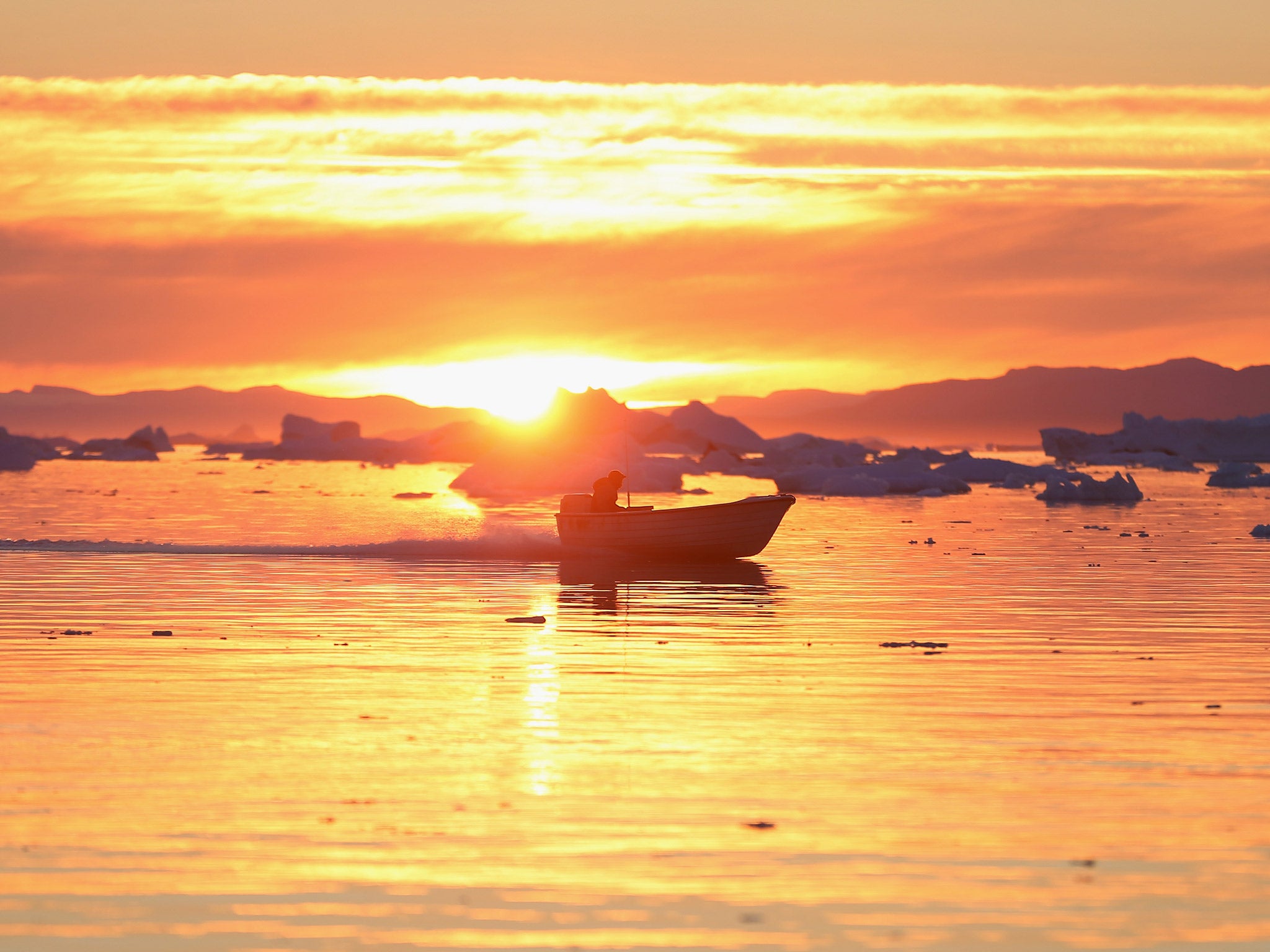 A boat cruises past icebergs that broke off from the Jakobshavn Glacier in Ilulissat, Greenland. The warmer temperatures that have had an effect on the glaciers in Greenland also have altered the ways in which the local populace farm, fish, hunt and even travel across land