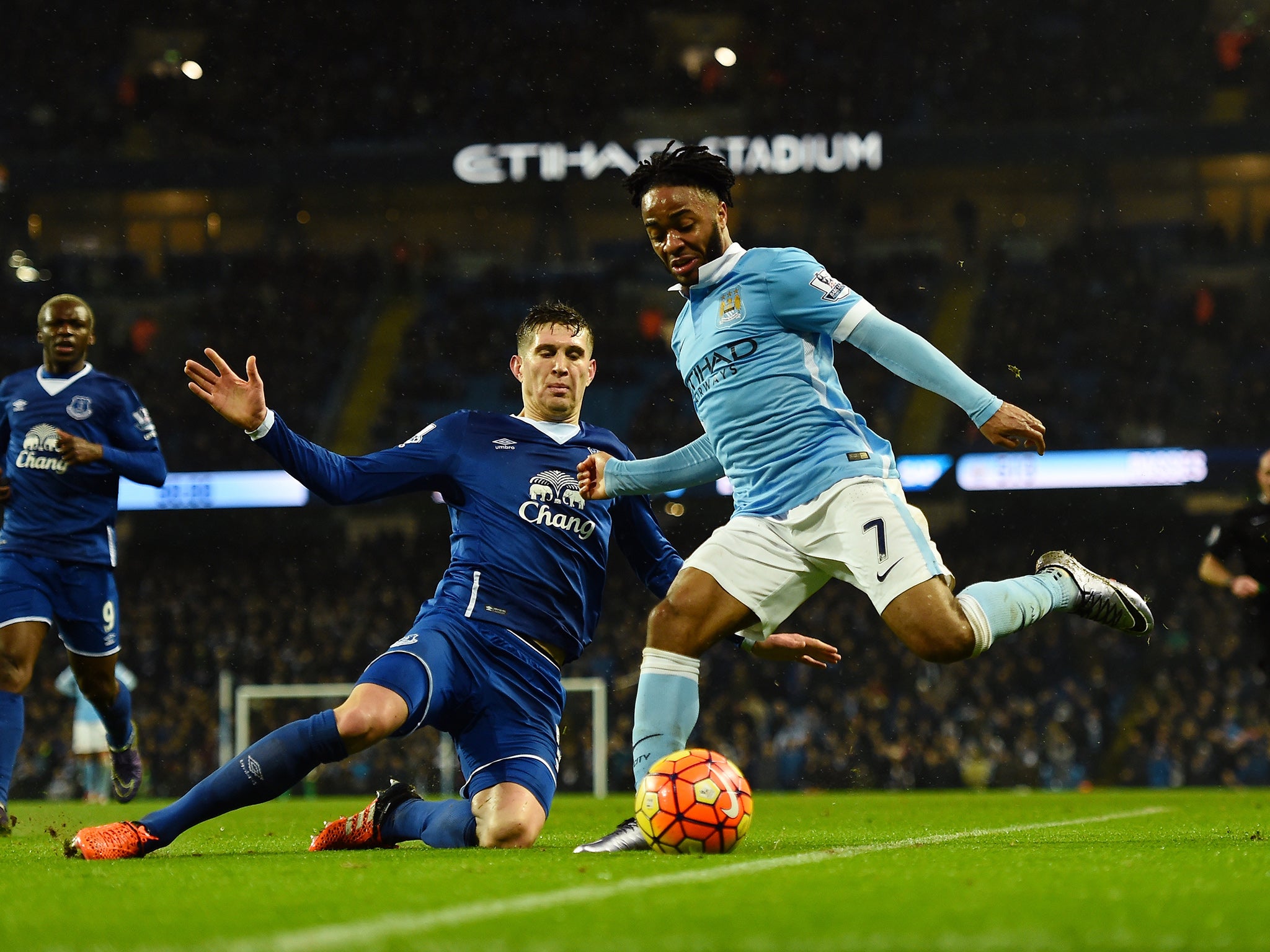 Manchester City's Raheem Sterling crosses under a tackle from Everton's John Stones