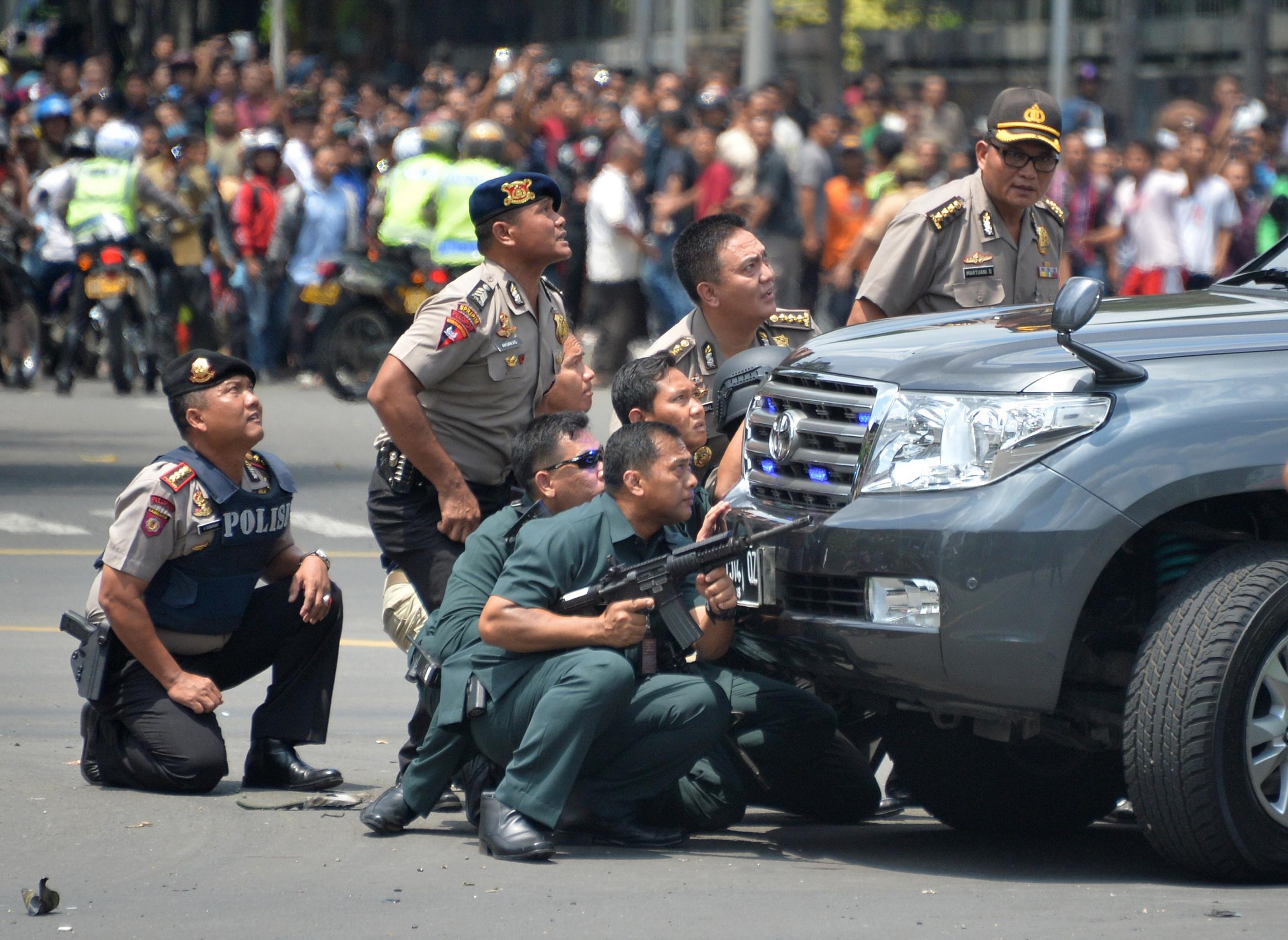 Police officers react near the site of a blast in Jakarta