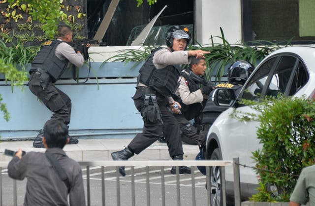 Indonesian police take position and aim their weapons as they pursue suspects