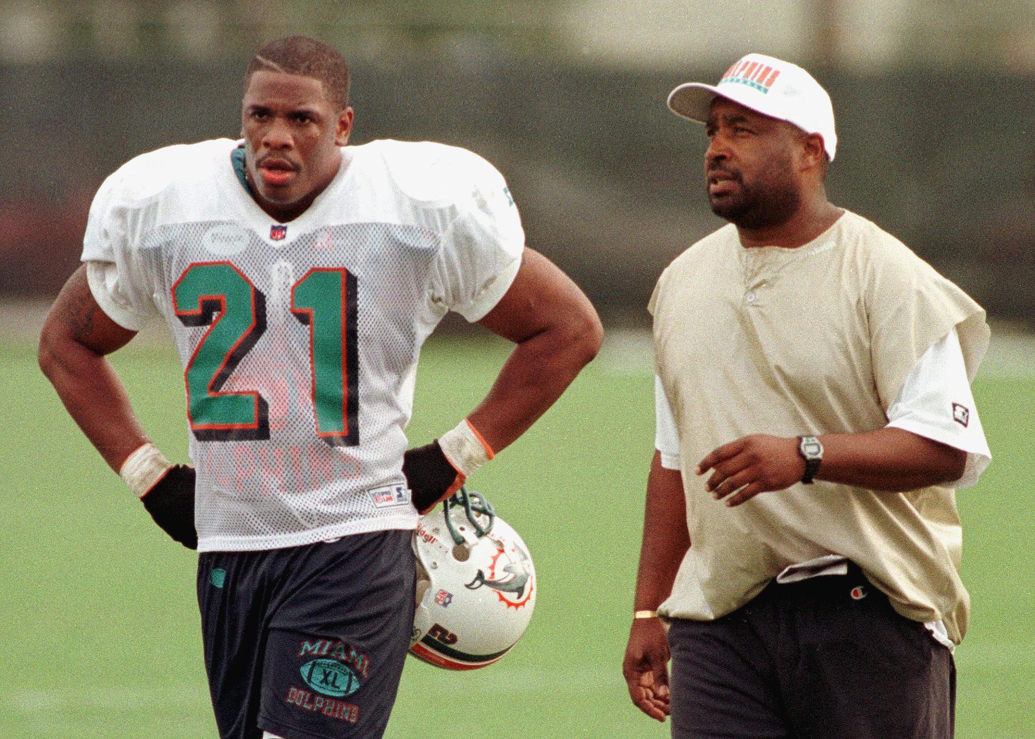 Lawrence Phillips (L) walks off the practice field with former coach Kippy Brown