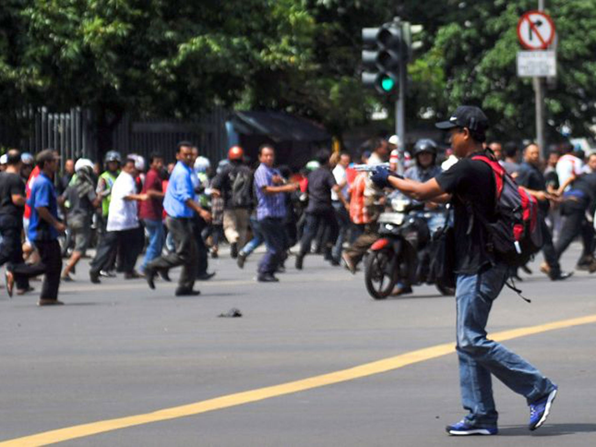 Moment of terror... a man points a gun towards a crowd of people in central Jakarta