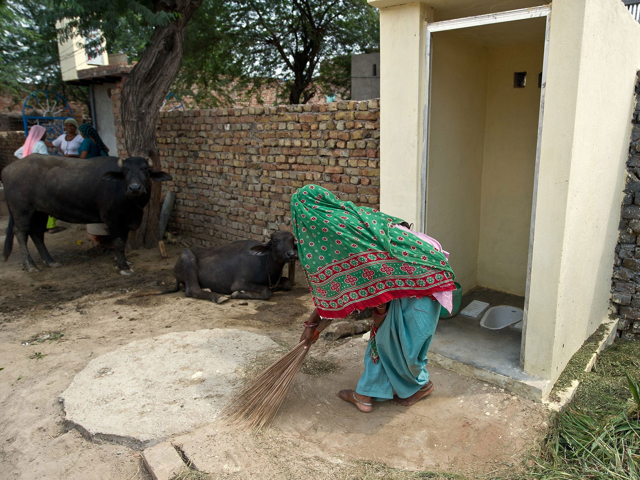 A woman sweeps by new public toilets in Mewat, Haryana.