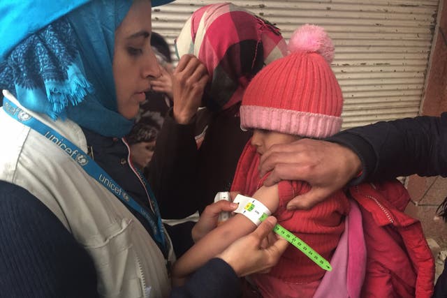 UNICEF employee measuring the arm of a malnourished child in the besieged Syrian town of Madaya, as they assess the health situation of residents of the famine-stricken town.
