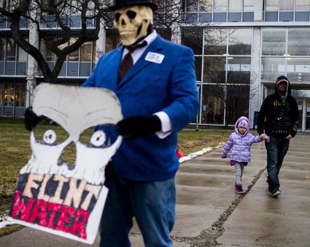 Flint resident Mike Hickey holds the hand of his daughter Natielee, 4, as they walk through pastactivists protest outside of City Hall to protest Michigan Gov. Rick Snyder's handling of the water crisis