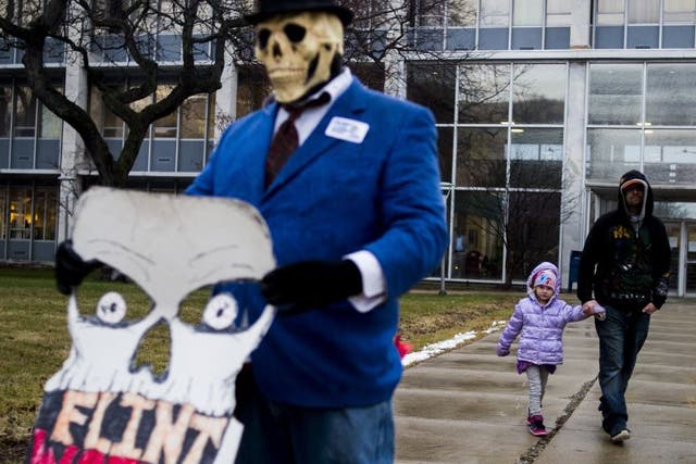 Flint resident Mike Hickey holds the hand of his daughter Natielee, 4, as they walk through pastactivists protest outside of City Hall to protest Michigan Gov. Rick Snyder's handling of the water crisis