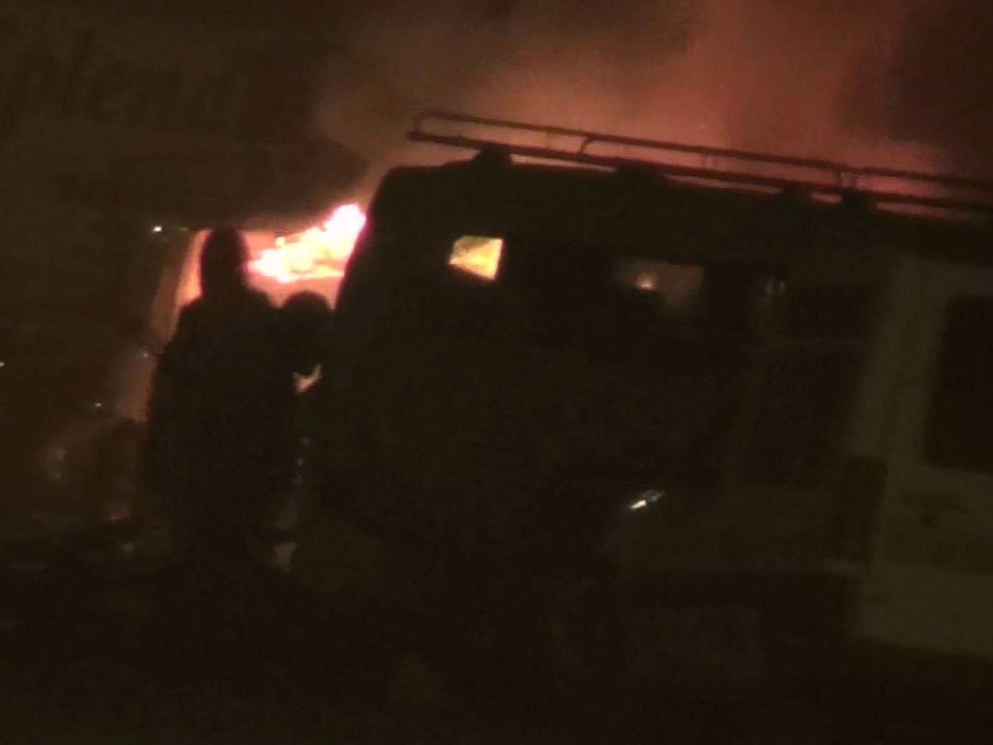 Two unidentified armed men approach a vehicle, near to a hotel, in Ouagadougou, Burkina Faso