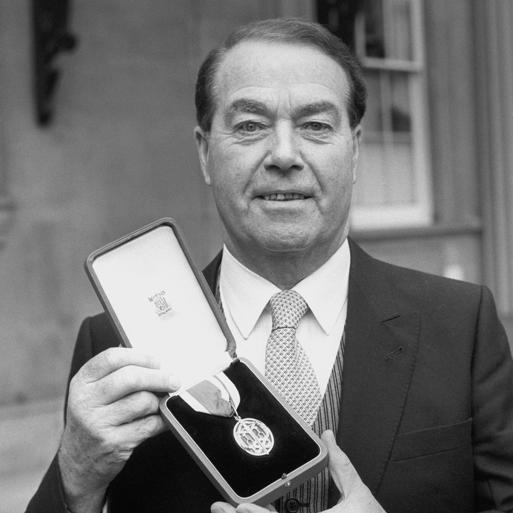 McQuarrie outside Buckingham Palace in 1987 after receiving his knighthood