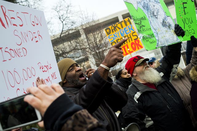 Flint, Michigan residents Arthur Woodson, left, and Tony Palladino Jr. protest the arrival of Flint native and filmmaker Michael Moore as Moore accuses Gov. Rick Snyder of poisoning Flint water during a rally outside of city hall in Flint, Mich.