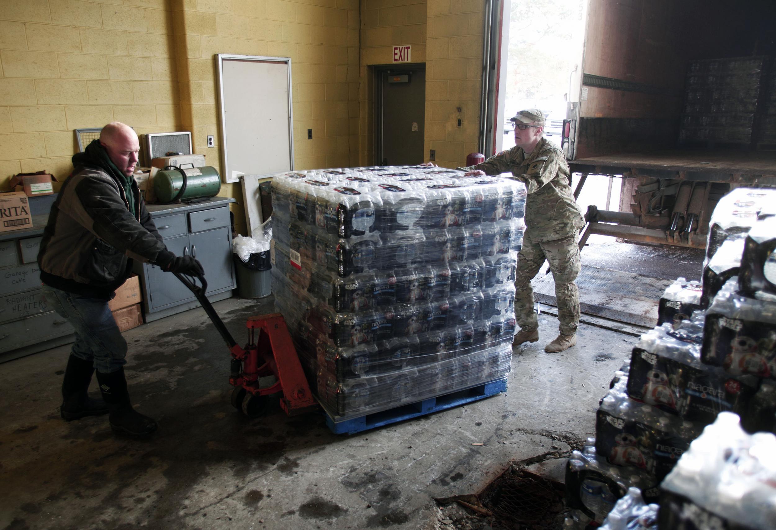 Volunteers help unload pallets of bottled water at a Flint Fire Station