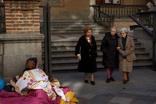 A woman begs in the street as women walk past on November 26, 2015 in Madrid, Spain. According to a recent study Madrid was ranked the most segregated city in Europe between rich and poor.
