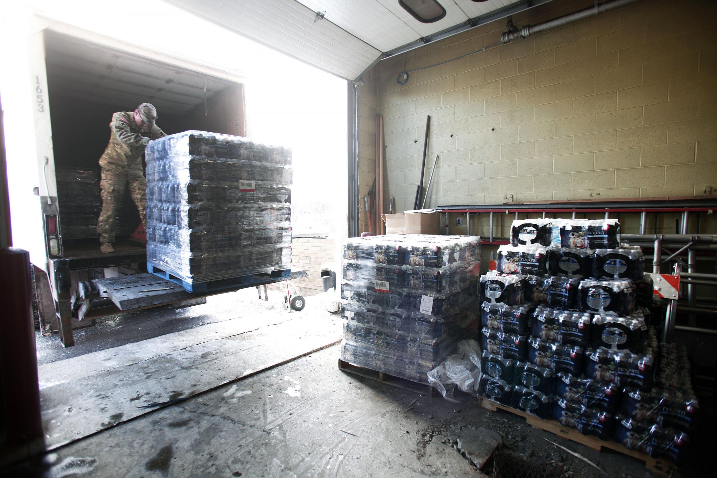 Michigan National Guard Staff Sergeant William Phillips helps unload pallets of bottled water at a Flint Fire Station