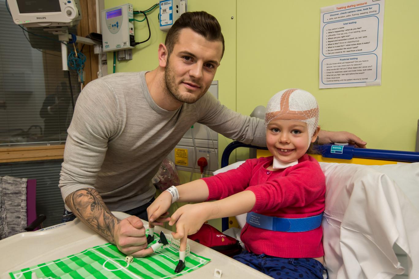 Jack Wilshere plays finger football with seven-year-old Chloe Evans, who has a rare condition affecting the central nervous system