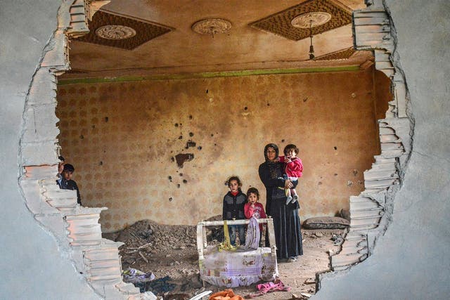 A women and her children stand in the ruins of battle-damaged house in the Kurdish town of Silopi
