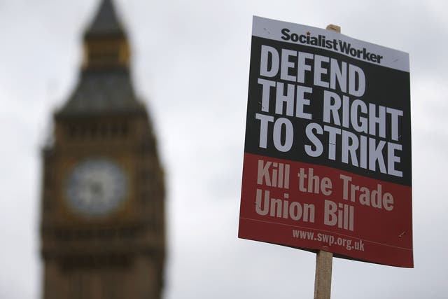 Protestors hold placards during an anti-trade union bill demonstration outside the Houses of Parliament in central London on 14 September, 2015