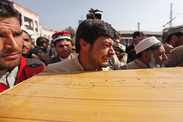 People move the body of a victim outside a hospital in Charsadda, Pakistan