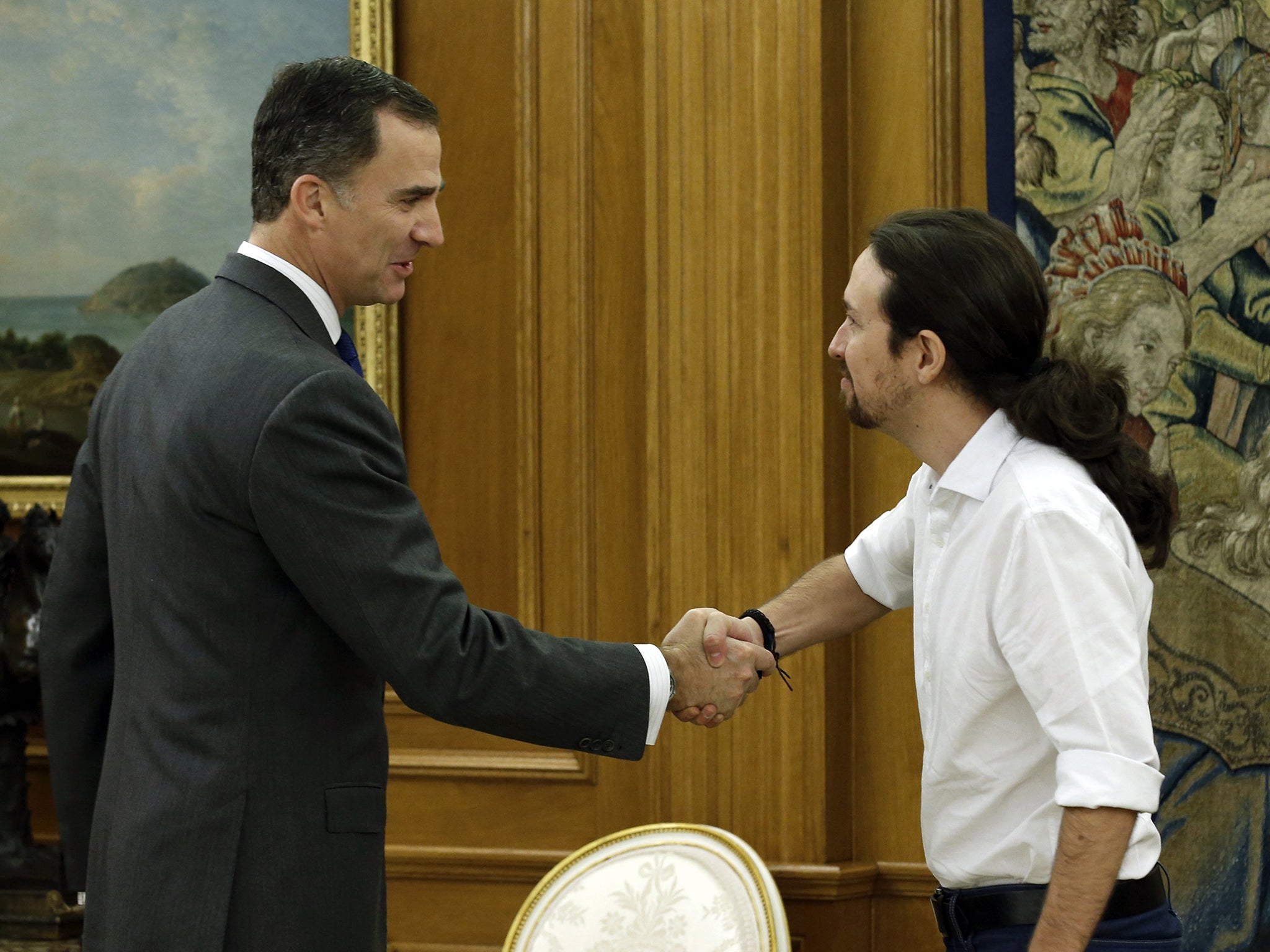 Spain's King Felipe VI, left, shakes hands with Podemos party leader Pablo Iglesias before a meeting at the Zarzuela Palace in Madrid