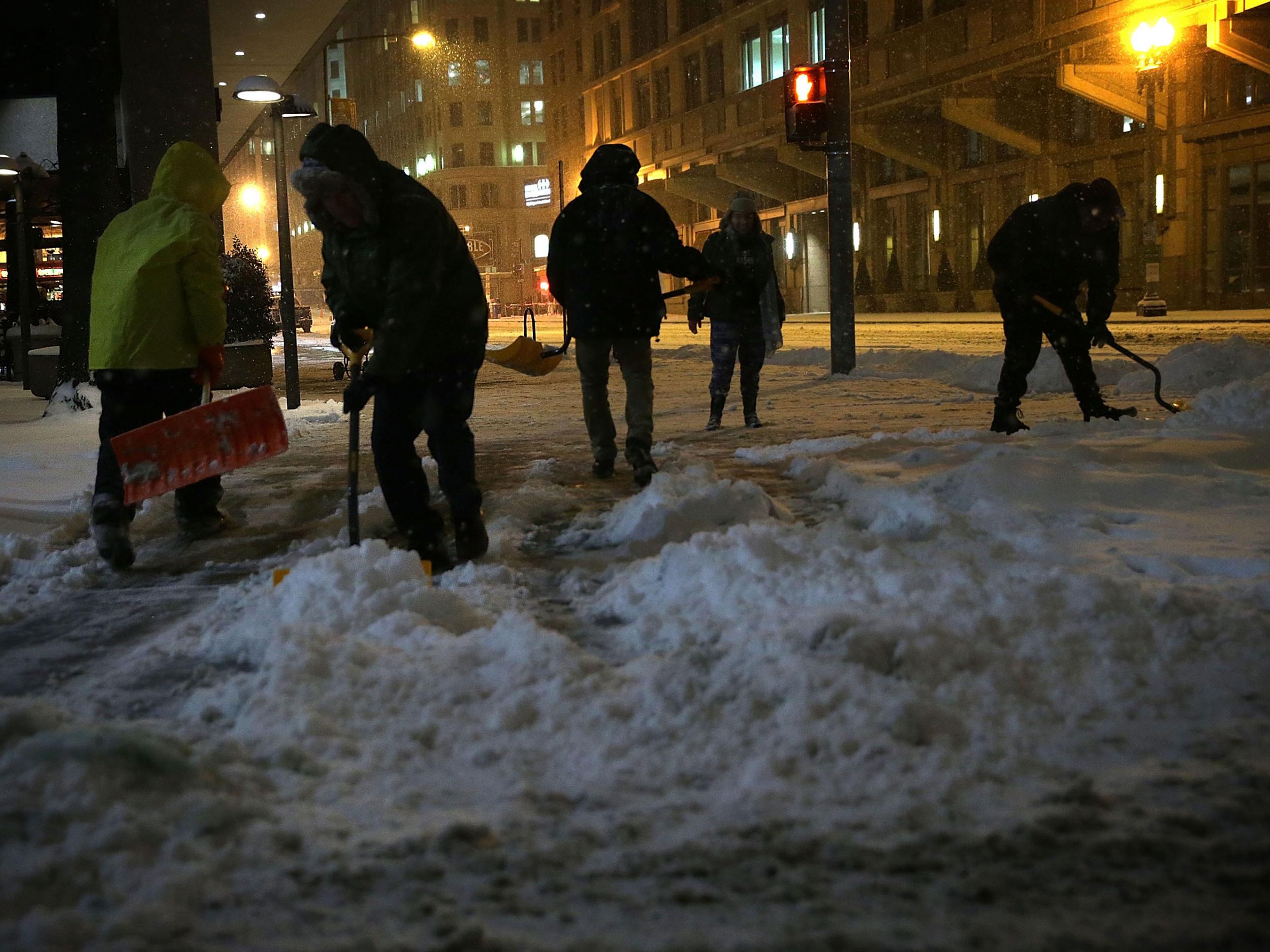 Workers shovels snow on a sidewalk January 22, 2016 in Washington, DC Getty