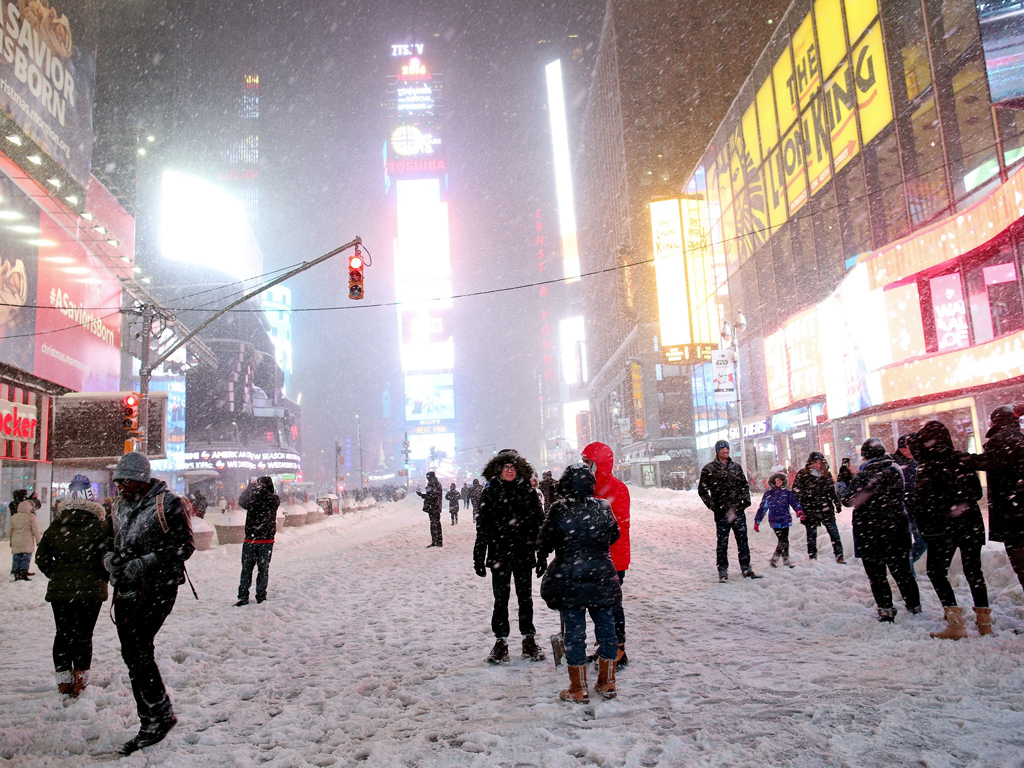 Pedestrians walk through the snowy streets near Times Square as all cars but emergency vehicles are banned from driving on the road on 23 January, 2016 in New York City