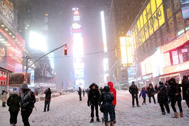 Pedestrians walk through the snowy streets near Times Square as all cars but emergency vehicles are banned from driving on the road on 23 January, 2016 in New York City