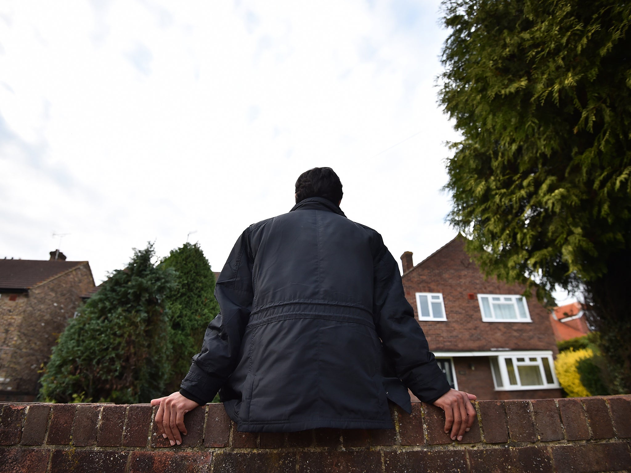 An asylum seeker sits on a wall outside his temporary accommodation (file pic)